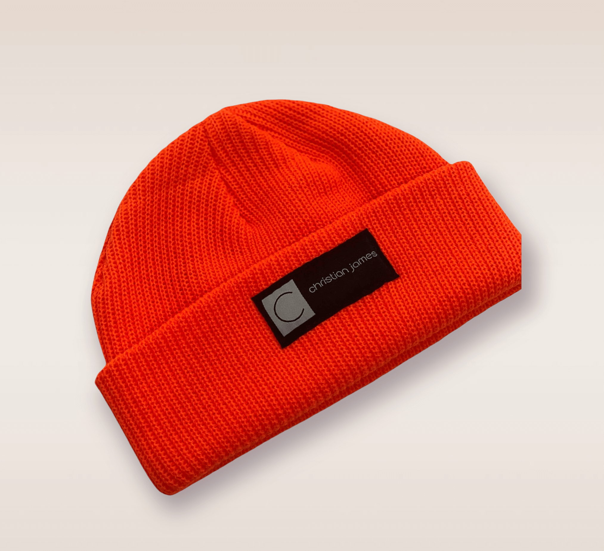In this up-close shot, we are introduced to the Red CJ beanie. A red knit hat featuring an embroidered patch of the brand's acronym in black and white. 