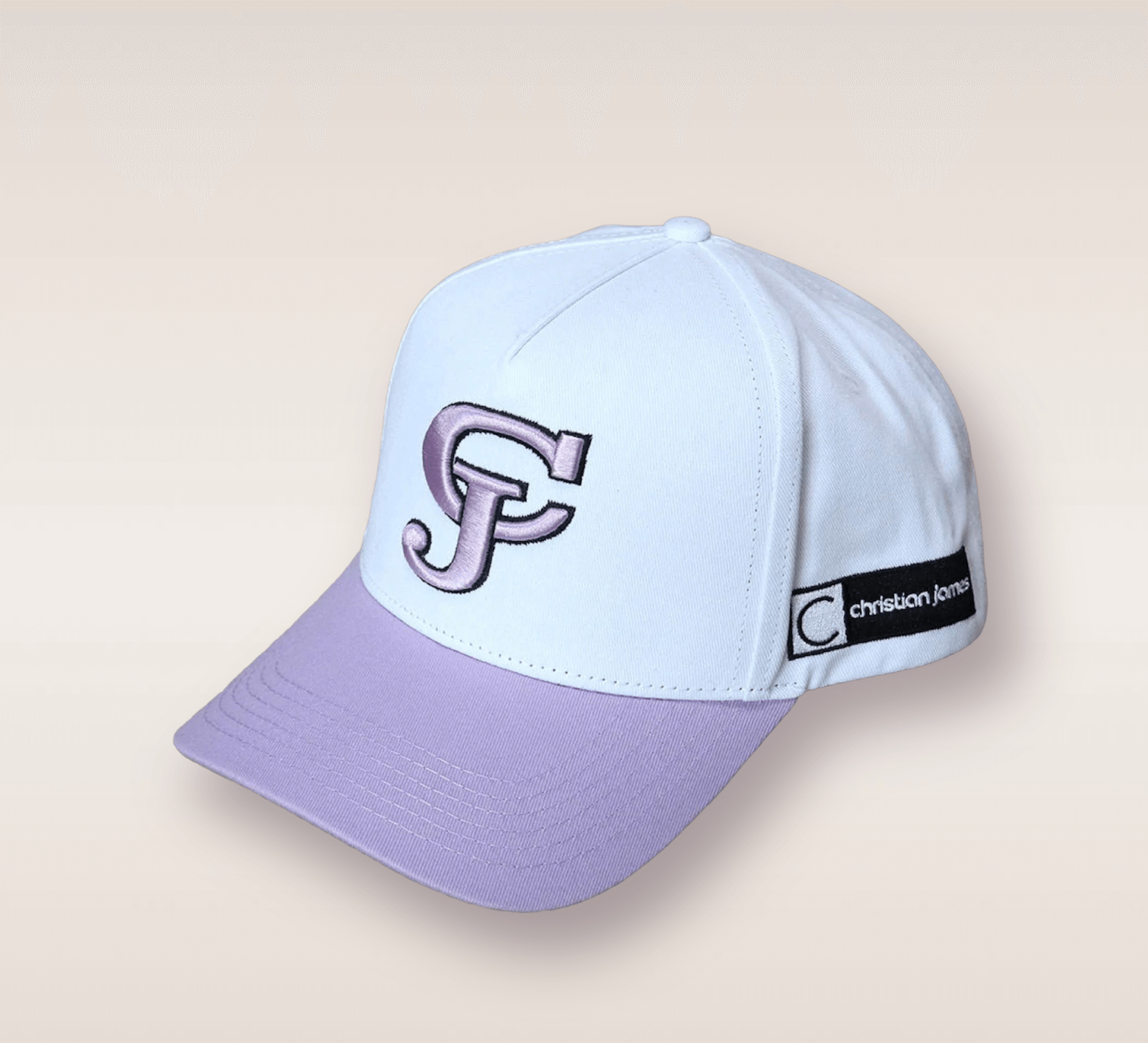 In this up-close shot, we are introduced to the Lavender Brim CJ Snapback. The hat features a white cap and a lavender brim. Embroidered in lavender lettering is the brand’s acronym 