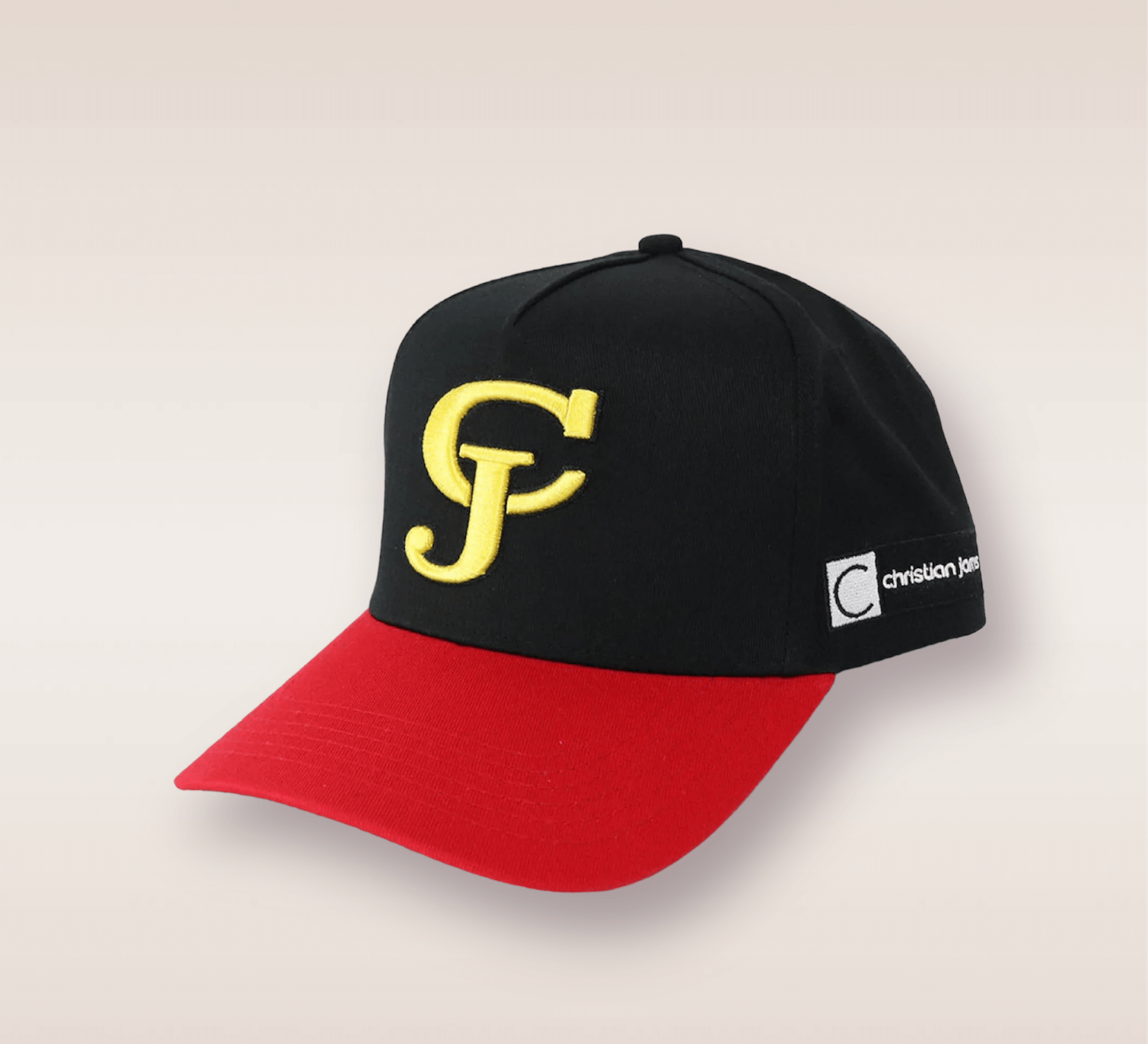 In this up-close shot, we are introduced to the Black and Red CJ Snapback. The hat features a Black cap and a red brim. Embroidered in yellow lettering is the brand’s acronym 